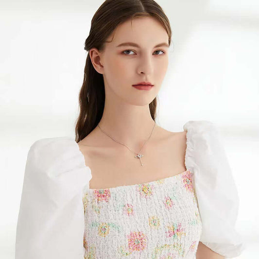 Moving Cupid Heart Angel Wings Tassel Necklace With Crystal worn by a model in a floral dress.