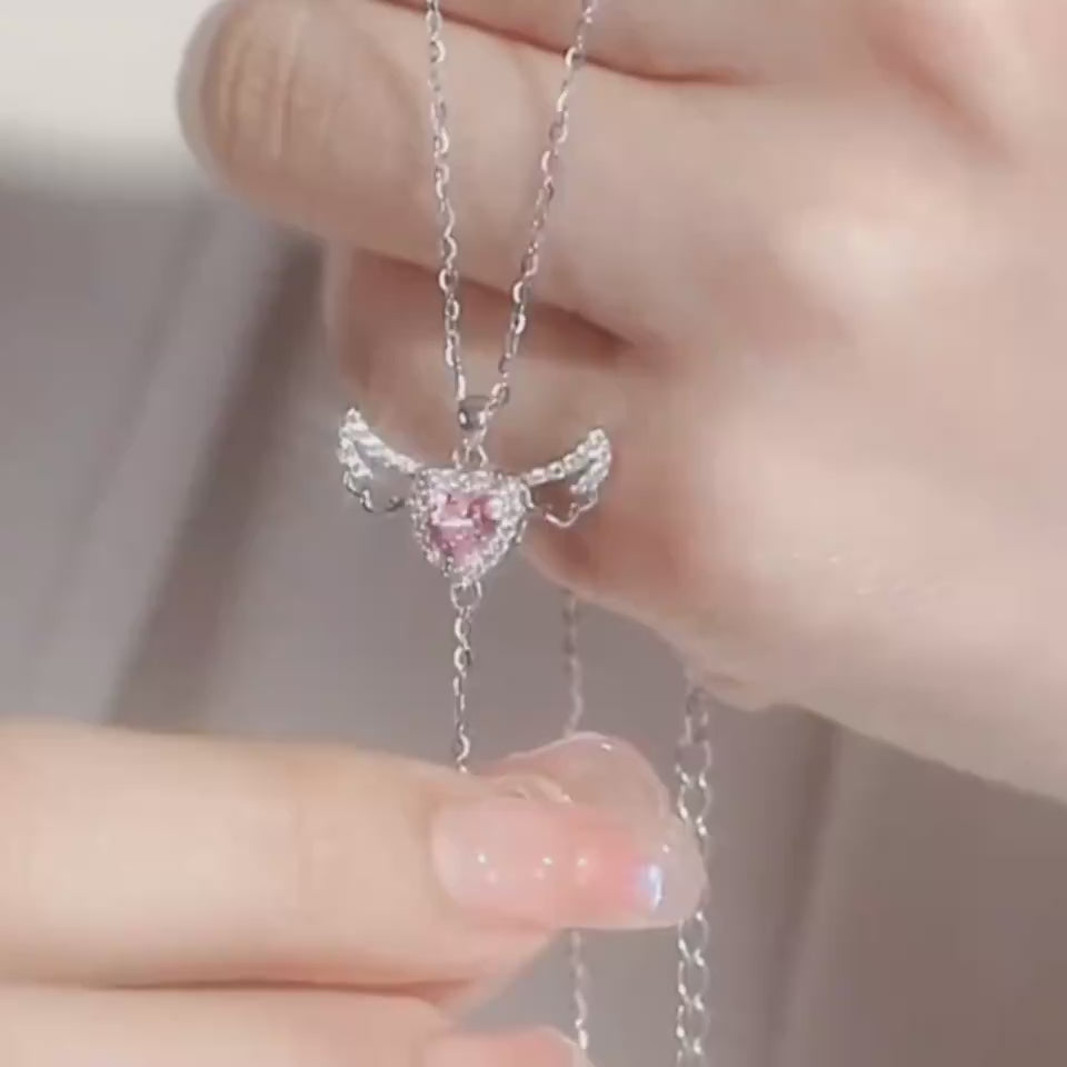 Moving Cupid Heart Angel Wings Tassel Necklace With Crystal held with delicate fingers, showcasing exquisite design and shine.
